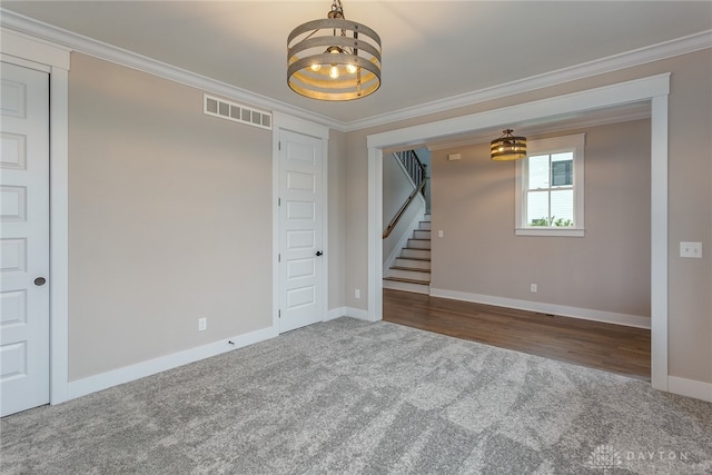 carpeted spare room featuring crown molding and a chandelier