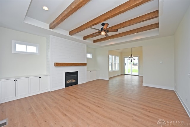 unfurnished living room with ceiling fan with notable chandelier, a healthy amount of sunlight, and light hardwood / wood-style floors