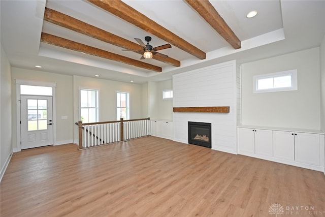 unfurnished living room featuring light hardwood / wood-style flooring, beam ceiling, and a healthy amount of sunlight