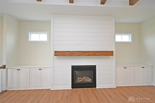 unfurnished living room with light wood-type flooring, a healthy amount of sunlight, and a large fireplace