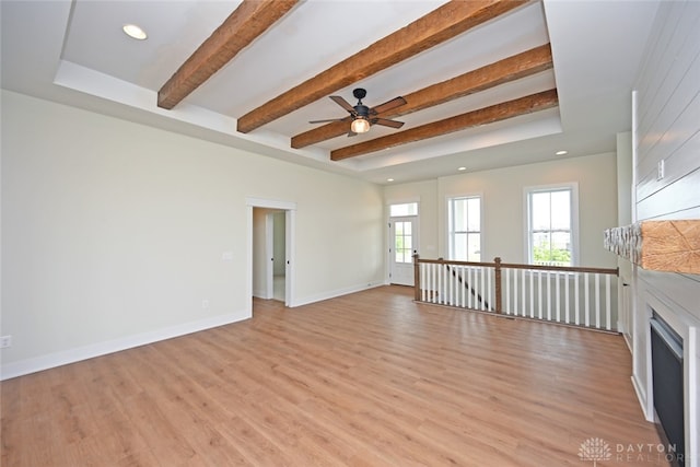 unfurnished living room with beamed ceiling, ceiling fan, and light hardwood / wood-style floors