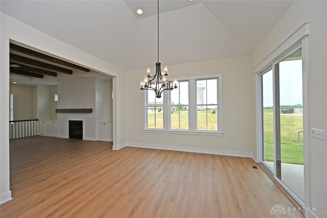 interior space featuring light wood-type flooring, vaulted ceiling with beams, a large fireplace, and a chandelier