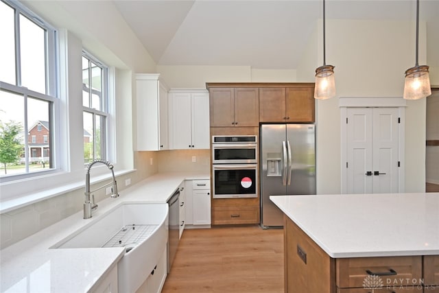 kitchen featuring white cabinetry, decorative light fixtures, and stainless steel appliances