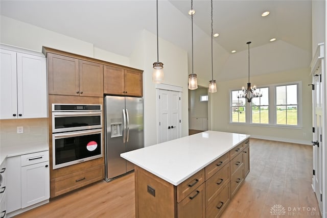 kitchen featuring appliances with stainless steel finishes, decorative light fixtures, light hardwood / wood-style flooring, and white cabinets