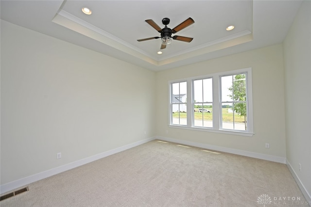 carpeted empty room with ornamental molding, ceiling fan, and a tray ceiling