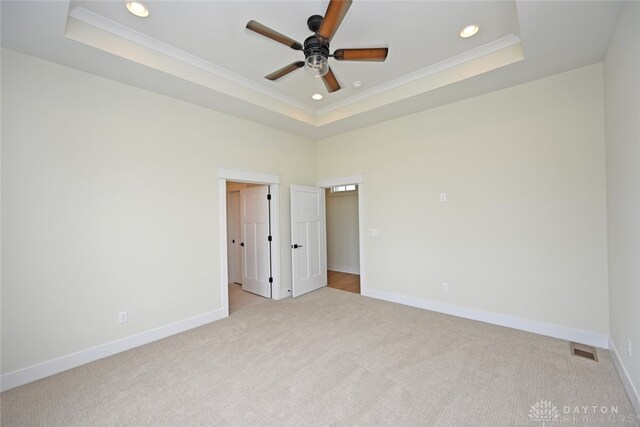 carpeted spare room featuring ceiling fan, a raised ceiling, and crown molding