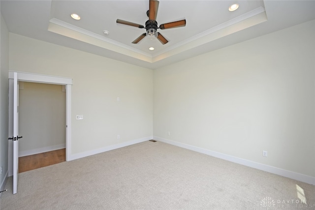 carpeted empty room featuring ceiling fan, a raised ceiling, and ornamental molding