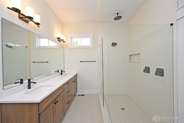 bathroom with tile patterned floors, a tile shower, and vanity