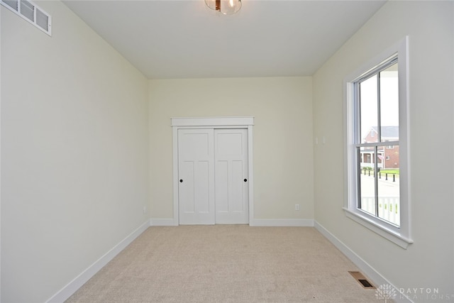 unfurnished bedroom featuring a closet and light colored carpet