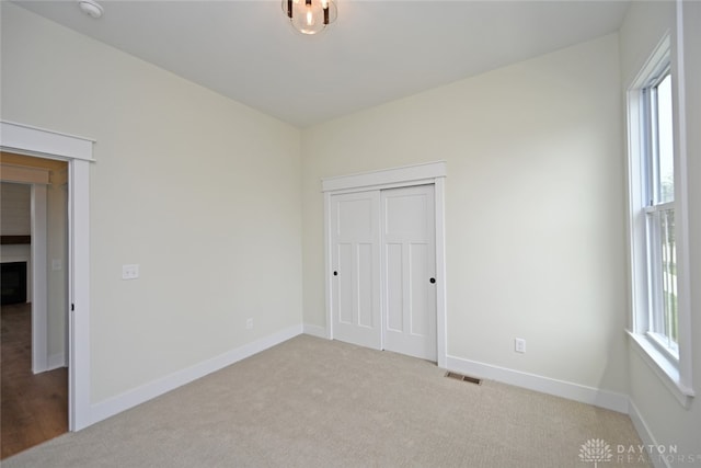 unfurnished bedroom featuring a closet, light colored carpet, and multiple windows