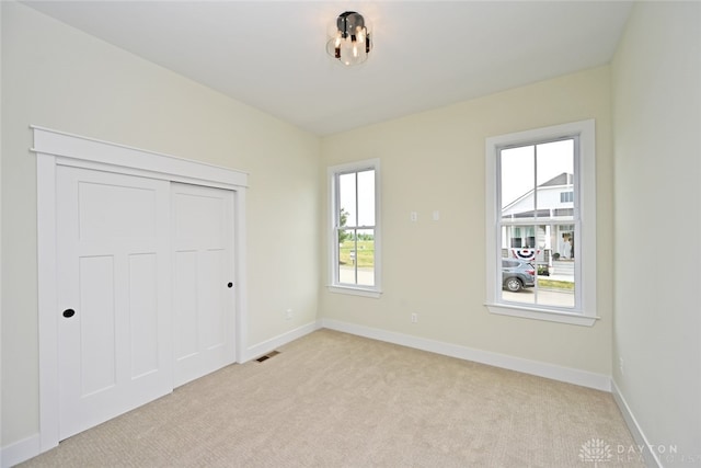 unfurnished bedroom featuring light carpet and a closet