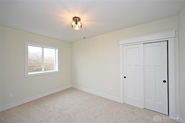 unfurnished bedroom featuring light carpet and a closet