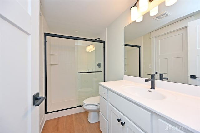 bathroom with a shower with door, hardwood / wood-style floors, vanity, and toilet