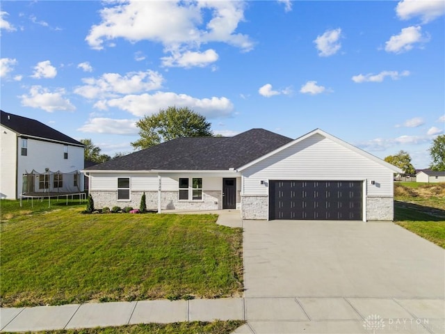 view of front of house featuring a garage, a trampoline, and a front lawn