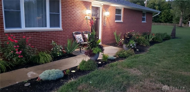 entrance to property featuring brick siding and a yard