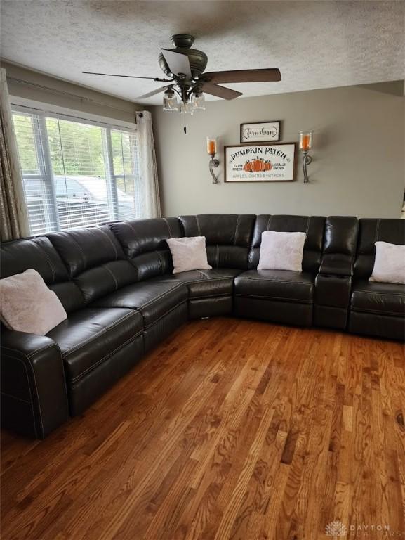 living room featuring a textured ceiling, ceiling fan, and wood finished floors