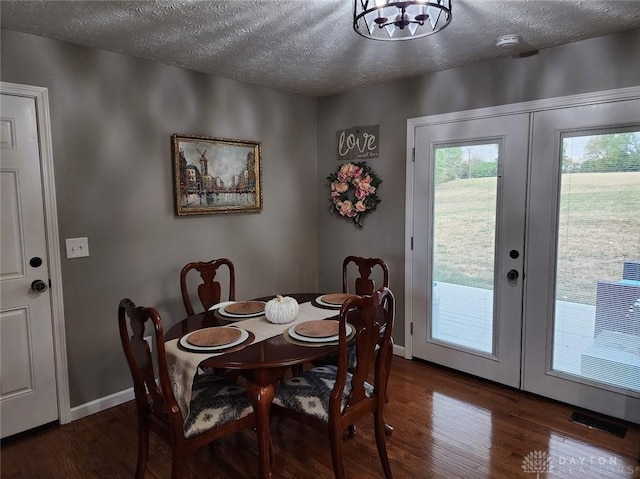 dining space featuring french doors, a textured ceiling, visible vents, and wood finished floors