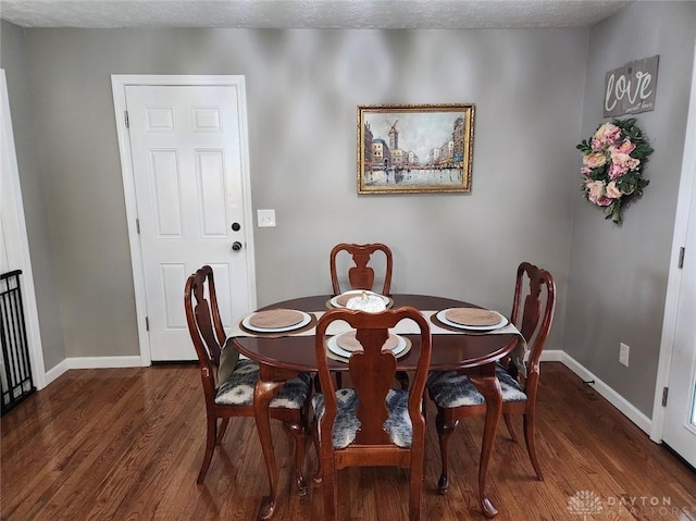 dining area featuring baseboards, a textured ceiling, and wood finished floors