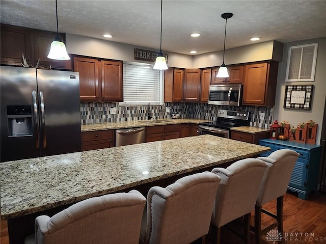 kitchen with a sink, a breakfast bar, dark wood-style floors, and stainless steel appliances