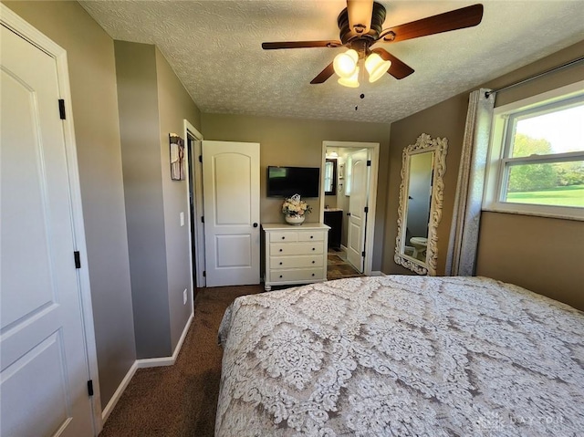 bedroom with a ceiling fan, a textured ceiling, ensuite bath, dark colored carpet, and baseboards