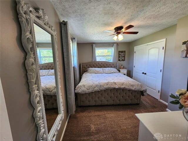 bedroom with dark colored carpet, baseboards, a textured ceiling, and ceiling fan