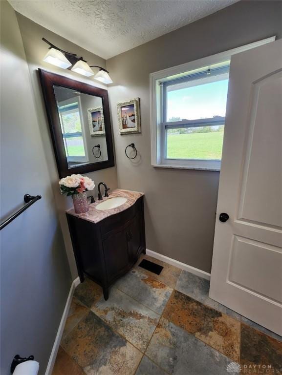 bathroom featuring a wealth of natural light, a textured ceiling, and baseboards