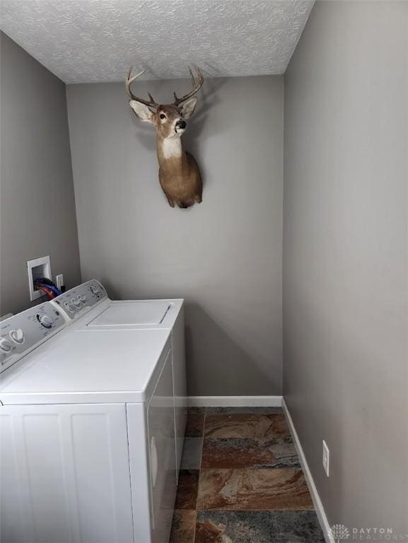 laundry room featuring washer and dryer, baseboards, a textured ceiling, and laundry area