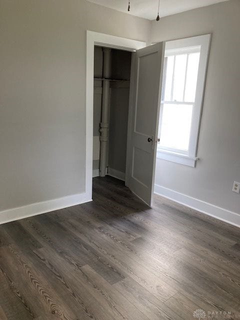 unfurnished bedroom featuring a closet and dark wood-type flooring