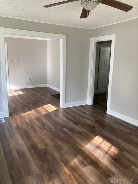 empty room with crown molding, ceiling fan, dark hardwood / wood-style floors, and a textured ceiling