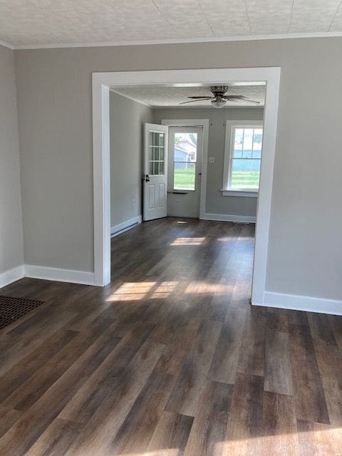 empty room with ceiling fan, dark hardwood / wood-style floors, and ornamental molding