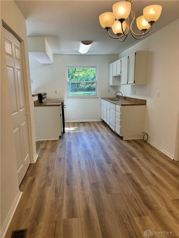 kitchen featuring white cabinetry, wood-type flooring, pendant lighting, electric stove, and sink