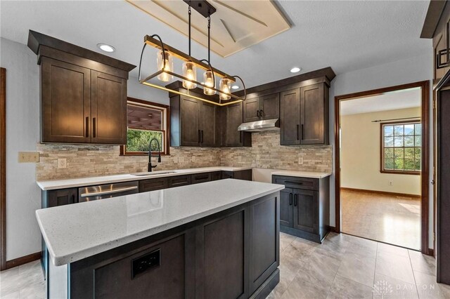 kitchen with a kitchen island, dark brown cabinets, decorative light fixtures, sink, and decorative backsplash