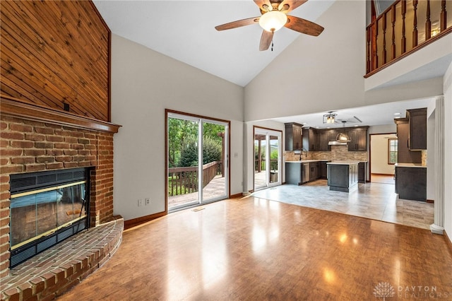 unfurnished living room featuring a fireplace, light hardwood / wood-style flooring, high vaulted ceiling, and sink