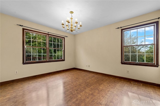 empty room featuring wood-type flooring and a chandelier