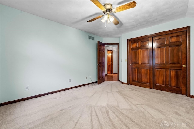 unfurnished bedroom featuring light carpet, ceiling fan, and a closet