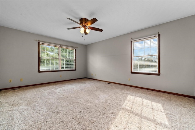 carpeted spare room featuring ceiling fan and a wealth of natural light