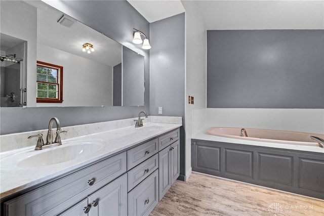 bathroom featuring a bathtub, vaulted ceiling, hardwood / wood-style flooring, and vanity