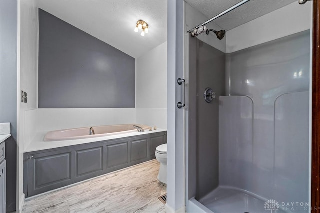 full bathroom featuring separate shower and tub, hardwood / wood-style floors, vanity, toilet, and a textured ceiling