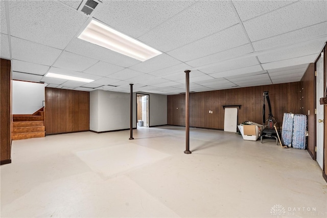 basement with wooden walls and a paneled ceiling