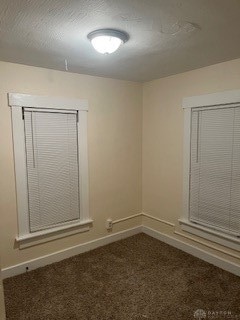 spare room with dark colored carpet