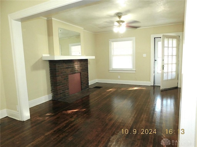 unfurnished living room featuring ceiling fan, dark hardwood / wood-style flooring, ornamental molding, and a brick fireplace