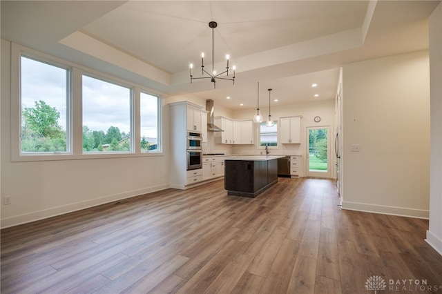 kitchen with wood-type flooring, decorative light fixtures, a kitchen island, and plenty of natural light