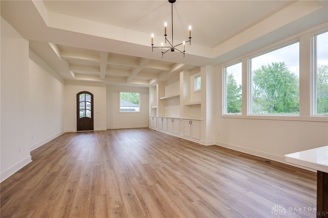 unfurnished living room with coffered ceiling, beam ceiling, a chandelier, and light hardwood / wood-style floors