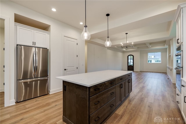 kitchen with hanging light fixtures, stainless steel refrigerator, dark brown cabinetry, and light hardwood / wood-style flooring