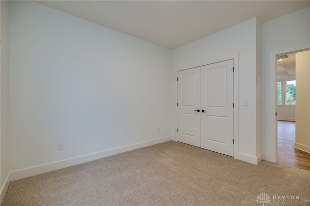 unfurnished bedroom with a closet and light carpet