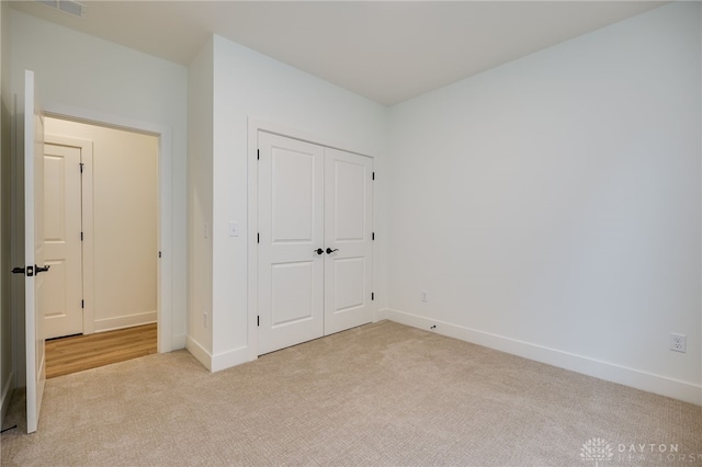 unfurnished bedroom featuring light colored carpet and a closet