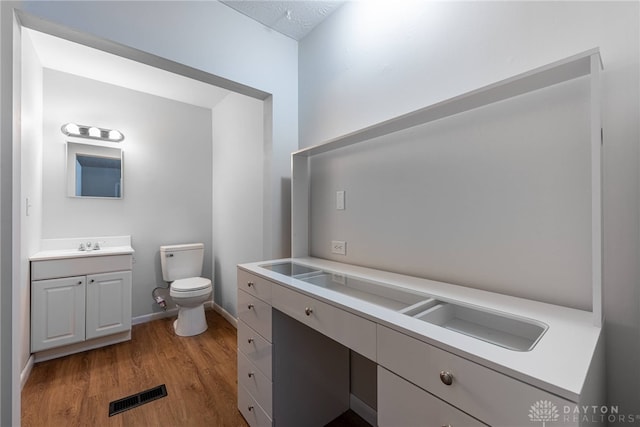 bathroom featuring toilet, hardwood / wood-style floors, and vanity