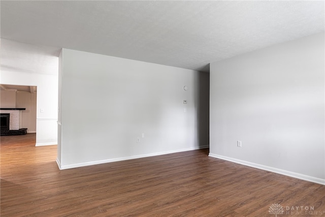 spare room featuring a fireplace and dark wood-type flooring