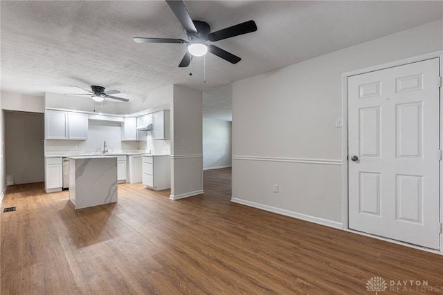 kitchen featuring a textured ceiling, hardwood / wood-style floors, a center island, white cabinetry, and ceiling fan