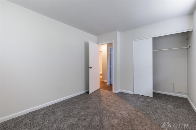 unfurnished bedroom featuring dark colored carpet and a closet